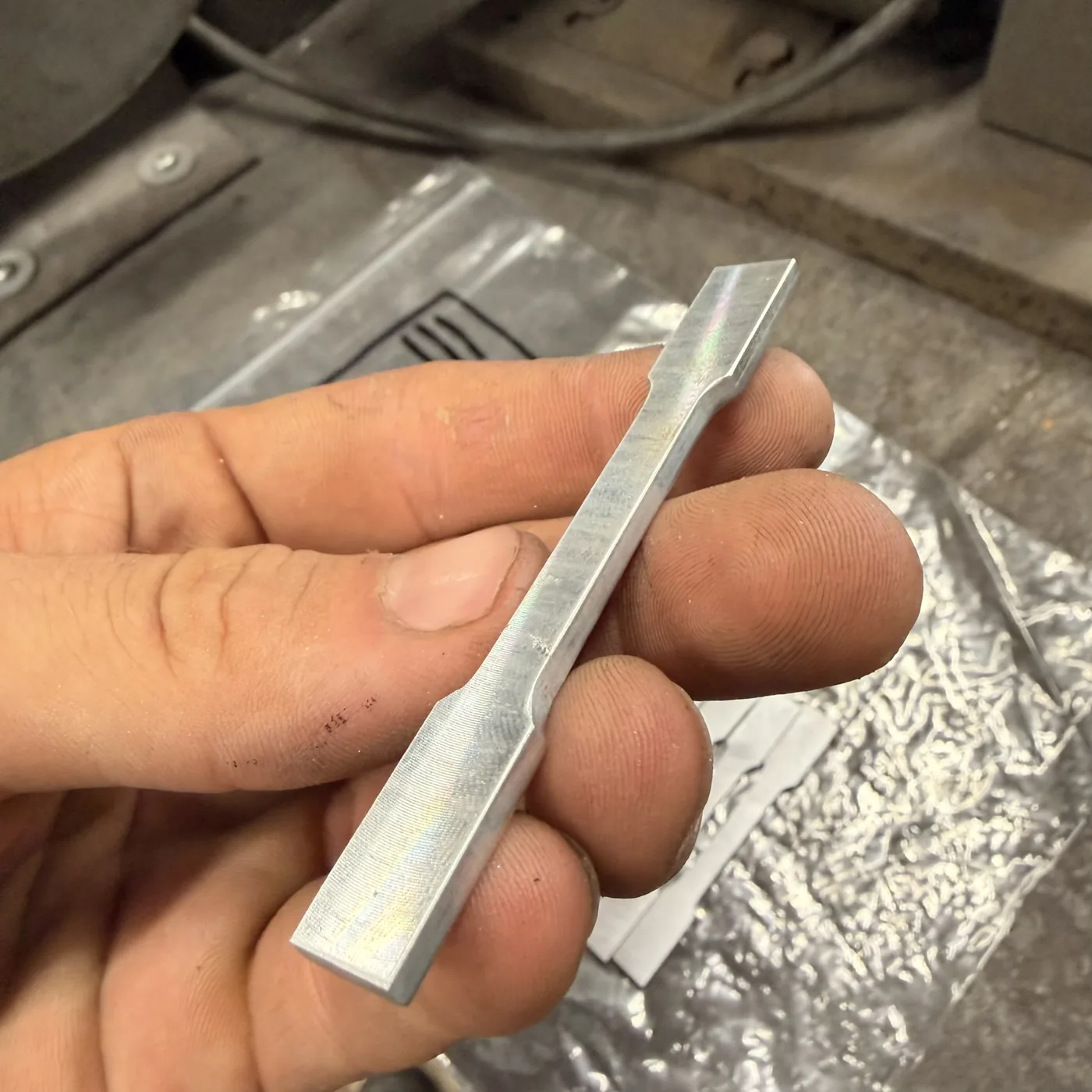 Small precision machined metal component held for close-up inspection